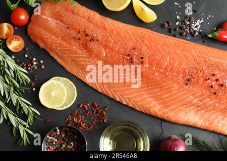 Frischer roher Lachs und Zutaten für Marinade auf schwarzem Tisch, flach liegend Stockfoto