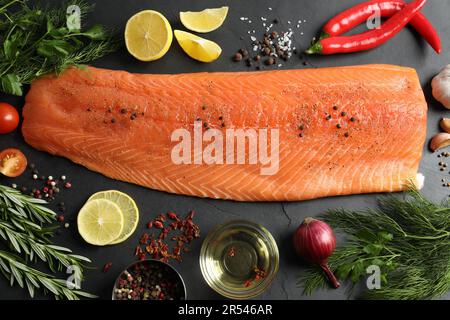 Frischer roher Lachs und Zutaten für Marinade auf schwarzem Tisch, flach liegend Stockfoto