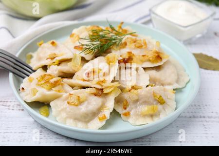 Gekochte Knödel (Varenyky) mit leckerer Füllung, gebratene Zwiebeln und Dill auf Holztisch, Nahaufnahme Stockfoto
