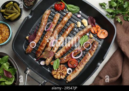 Grillpfanne mit leckeren Würstchen, Gewürzen und Gemüse auf einem leichten Tisch, flach liegend Stockfoto