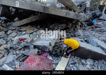 Gaza, Palästina. 31. Mai 2023. Ein palästinensischer Junge versucht, sein Fahrrad unter den Trümmern ihrer zerstörten Wohngebäude zu ziehen, nachdem die Israelis in Gaza City zugeschlagen haben. Israel und die islamische Dschihad-Bewegung einigten sich Ende Mai auf einen von Ägyptern vermittelten Waffenstillstand. Israel hat als Reaktion auf den Abschuss von Raketen vom Gazastreifen nach Israel mehrere Angriffe auf die militärische Führung der palästinensischen Islamischen Dschihad-Bewegung verübt. Die Auswirkungen der israelischen Razzien auf Gaza am 12. Mai 2023. Kredit: SOPA Images Limited/Alamy Live News Stockfoto