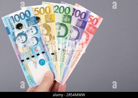 Philippinisches Geld - Peso in der Hand auf grauem Hintergrund Stockfoto