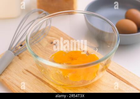 Eine Frau, die Eier in einer Glasschüssel schlägt. Junge Frau, die in der Küche kocht. Stockfoto