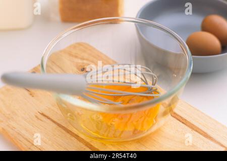 Eine Frau, die Eier in einer Glasschüssel schlägt. Junge Frau, die in der Küche kocht. Stockfoto