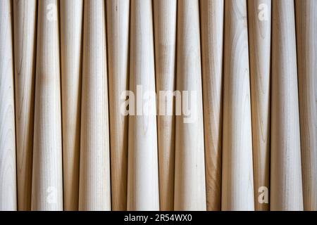 Das Muster polierter konischer Tischbeine aus Holz als Hintergrundebene. Vorbereitete Möbeldetails in der Möbelfabrik Stockfoto