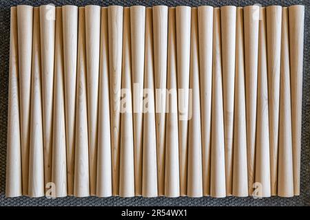 Muster polierter konischer Tischbeine aus Holz auf der grauen Teppichoberansicht. Vorbereitete Möbeldetails in der Möbelfabrik Stockfoto