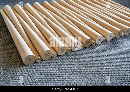 Muster polierter konischer Tischbeine aus Holz auf dem grauen Teppich in der Nahaufnahme. Vorbereitete Möbeldetails in der Möbelfabrik Stockfoto