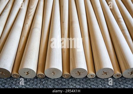 Muster polierter konischer Tischbeine aus Holz auf dem grauen Teppich in der Nahaufnahme. Vorbereitete Möbeldetails in der Möbelfabrik Stockfoto