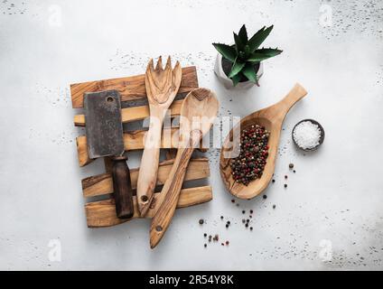 Olivenbaumtablett mit Kochutensilien und Fleischbeil im Küchenhintergrund. Stockfoto