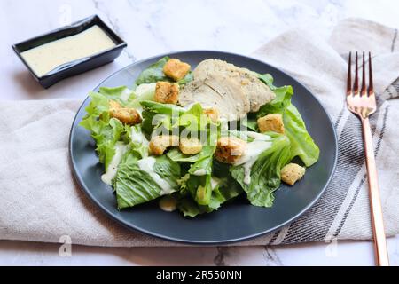 Caesar Salad mit weißem Hühnerfleisch aus nächster Nähe auf dem Marmortisch - gesunde Ernährung Stockfoto