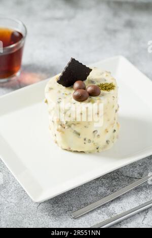 Ein-Personen-Minikuchen mit Pistazien und weißer Schokolade auf einem weißen Porzellanteller Stockfoto