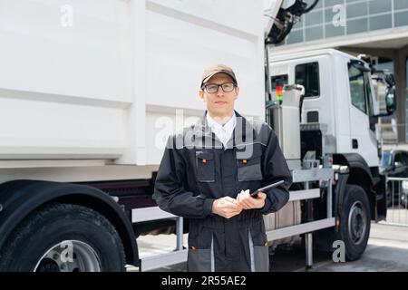 Manager mit einem digitalen Tablet neben dem Müllwagen. Hochwertiges Foto Stockfoto