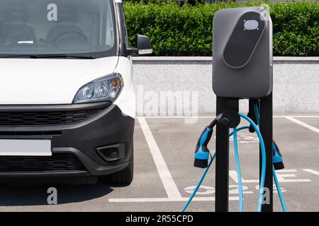 Elektrischer Lieferwagen mit Ladestation für Elektrofahrzeuge. Hochwertiges Foto Stockfoto