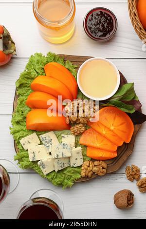 Köstliche Persimone, Blauschimmelkäse, Nüsse und Honig, serviert auf einem weißen Holztisch, flach liegend Stockfoto