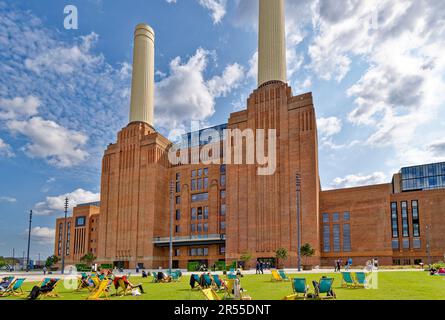 London Wandsworth Battersea Power Station Sonnenschein blauer Himmel und Menschen in Liegestühlen auf einem grünen Rasen Stockfoto