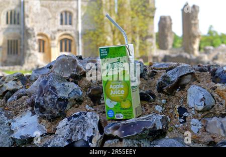 Ein leerer Apfelsaftkarton mit Papierstroh, der auf den Wandruinen von Binham Priory in North Norfolk in Binham, Norfolk, England, Großbritannien, zurückgelassen wurde. Stockfoto