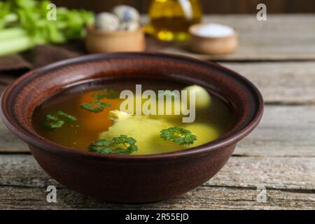 Köstliches Hühnerbouillon mit Petersilie, Karotte und Eiern auf einem Holztisch, Nahaufnahme Stockfoto