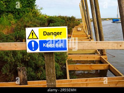 Hinweis auf Gefahr und durch Bau und Austausch von Bereitstellungs- und Verankerungseinrichtungen am Wasser in Blakeney, Norfolk, England, Großbritannien, fernhalten. Stockfoto