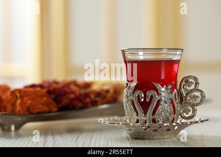 Ein Glas traditioneller türkischer Tee im alten Halter auf einem weißen Holztisch. Platz für Text Stockfoto