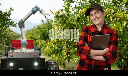 Der Landwirt steuert den autonomen Mähroboter mit einem Roboterarm, der Äpfel auf einem intelligenten Bauernhof erntet. Konzept. Stockfoto