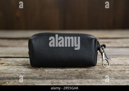Eleganter schwarzer Schlüsselhalter aus Leder auf altem Holztisch, Nahaufnahme Stockfoto