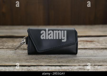 Eleganter schwarzer Schlüsselhalter aus Leder auf altem Holztisch, Nahaufnahme Stockfoto