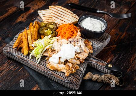 Kebab, Shawarma, gegrilltes Gyro-Fleisch mit pommes und Gemüse auf einem Holzbrett. Holzhintergrund. Draufsicht. Stockfoto