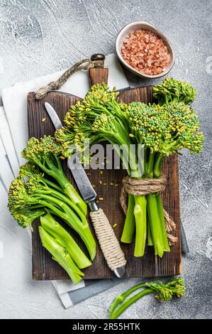 Frischer Broccolini-Sprossen auf dem Schneidebrett, bereit zum Kochen. Weißer Hintergrund. Draufsicht. Stockfoto