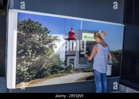 Crozon (Bretagne, Nordwestfrankreich): Frau, die Geld von einer Credit agricole-Kasse in Morgat abhebt. Ein Bild des Leuchtturms Morgat Stockfoto