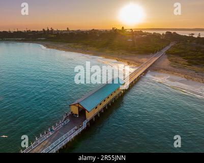 Luftaufnahme eines Zwerghauses auf einem schmalen Pier über einer ruhigen Bucht bei Sonnenuntergang in Queenscliff in Victoria, Australien Stockfoto