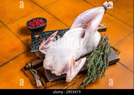 Farm Rohe Guineafowl, Perlhühner mit Kräutern zum Kochen. Orangefarbener Hintergrund. Draufsicht. Stockfoto