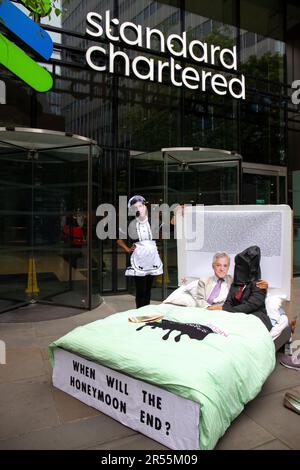 London, England, Großbritannien 01/06/2023 Money Rebellion Aktivisten veranstalten bei Standard Chartered eine satirische „Menage a trois“ zwischen dem CEO Bill Winters und seinen fossilen Brennstofffreunden, Öl und Kohle, während Rishi Sunak Champagner serviert und gelegentlich mit einem Haufen Geld angeboten wird. Stockfoto