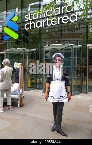 London, England, Großbritannien 01/06/2023 Money Rebellion Aktivisten veranstalten bei Standard Chartered eine satirische „Menage a trois“ zwischen dem CEO Bill Winters und seinen fossilen Brennstofffreunden, Öl und Kohle, während Rishi Sunak Champagner serviert und gelegentlich mit einem Haufen Geld angeboten wird. Stockfoto