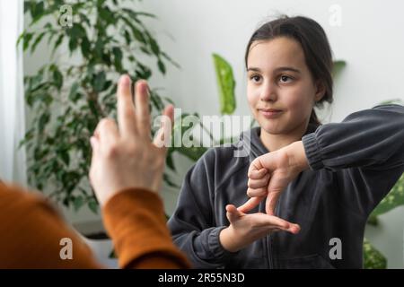 Kleines, kaukasisches Teenager-Kind Machen Sie zu Hause Artikulationsübungen mit einer fürsorglichen Mutter oder einer fürsorglichen Lehrerin. Das kleine Kind spricht Geräusche aus, spricht mit dem Lehrer oder Stockfoto