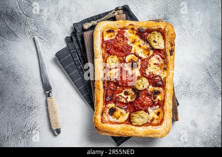 Vegetarische Blätterteigpizza mit Artischocke, Mozzarella, Tomaten und Käse. Weißer Hintergrund. Draufsicht. Stockfoto