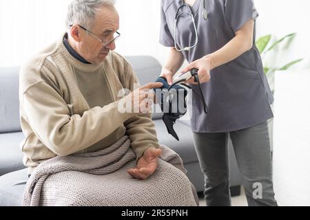 Krankenschwester messen den hohen Blutdruck eines kranken älteren, reifen männlichen Patienten in der klinischen Nahaufnahme. Arzt zur Kontrolle des arteriellen Blutdrucks im Alter Stockfoto