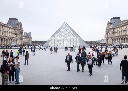 Die berühmte Louvre-Pyramide und das elegante Palais Royale stehen an einem ruhigen grauen Frühlingstag in Paris, Frankreich, Seite an Seite. Inmitten einer belebten Menschenmenge von Besuchern und Touristen verbinden diese architektonischen Meisterwerke Modernität und Geschichte und laden zu Entdeckungen und Wertschätzung ein. Erleben Sie die harmonische Mischung aus Alt und Neu, während das reiche kulturelle Erbe der Stadt inmitten der pulsierenden Energie eines beliebten Reiseziels zum Leben erwacht. Stockfoto