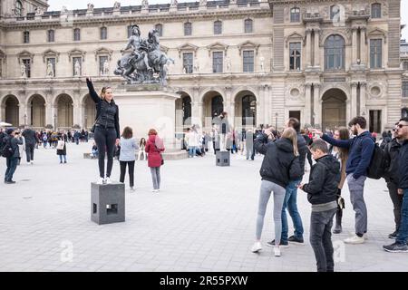 Touristen machen Fotos vor der Pyramide des Lovre im Innenhof des eleganten Palais Royale, die an einem ruhigen grauen Frühlingstag in Paris auf den Eintritt in das Kunstmuseum des Louvre warten. Inmitten einer belebten Menschenmenge von Besuchern und Touristen verbinden diese architektonischen Meisterwerke Modernität und Geschichte und laden zu Entdeckungen und Wertschätzung ein. Erleben Sie die harmonische Mischung aus Alt und Neu, während das reiche kulturelle Erbe der Stadt inmitten der pulsierenden Energie eines beliebten Reiseziels zum Leben erwacht. Stockfoto