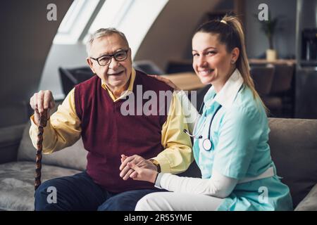 Die Pflegekraft hilft dem alten Mann zu Hause. Professionelle Gesundheitsförderung für ältere Menschen. Stockfoto