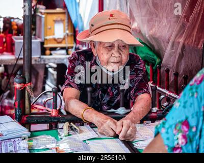 Bangkok, Thailand. 9. Februar 2022. Eine thailändische Großmutter hat auf der Straße des Khlong Toei Markts, dem größten Frischmarkt von BangkokÃ, auf der Rama IV Road Lotteriekarten verkauft. (Kreditbild: © Nathalie Jamois/SOPA Images via ZUMA Press Wire) NUR REDAKTIONELLE VERWENDUNG! Nicht für den kommerziellen GEBRAUCH! Stockfoto