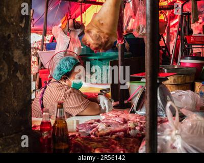 Bangkok, Thailand. 9. Februar 2022. Eine örtliche Metzgerin an ihrem Stand beobachtet ihr Smartphone auf dem Khlong Toei Markt, dem größten Frischmarkt von BangkokÃ, auf der Rama IV Road. (Kreditbild: © Nathalie Jamois/SOPA Images via ZUMA Press Wire) NUR REDAKTIONELLE VERWENDUNG! Nicht für den kommerziellen GEBRAUCH! Stockfoto