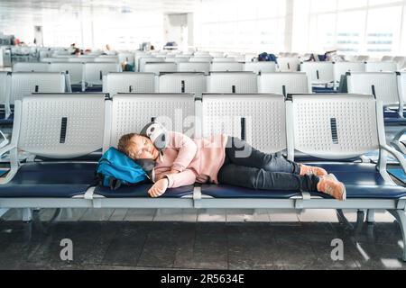 Kind, Teenager, müde, schlafendes Mädchen, wartet in der Abflughalle des Flughafenterminals mit Rucksack. Sitzen auf Stühlen in einem Reisekissen im Flugzeug. Flug Stockfoto