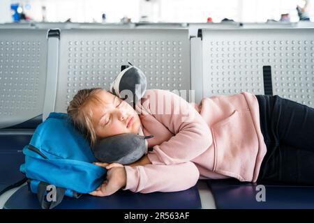 Kind, Teenager, müde, schlafendes Mädchen, wartet in der Abflughalle des Flughafenterminals mit Rucksack. Sitzen auf Stühlen in einem Reisekissen im Flugzeug. Flug Stockfoto