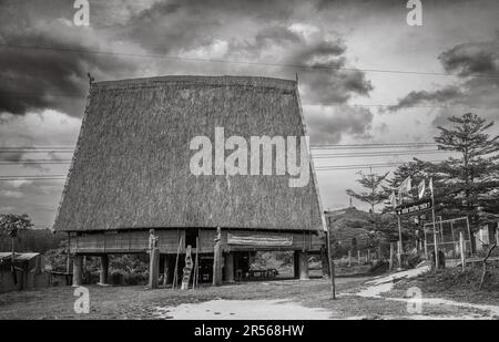Ein traditionelles „nha rong“, oder Kulturhaus, mit seinem segelähnlichen Strohdach, das der ethnischen Minderheit Bahnar neben dem Dorf gehört Stockfoto