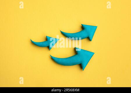 Foto von 3 grünen Pfeilen aus Plastik, die nach oben zeigen. 3D-Modell, Pfeilzeichen zeigt zunehmende Richtung auf gelbem Hintergrund. Entwicklungskonzept, Stockfoto