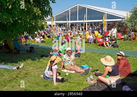 Menschen, die sich beim Hay Book Festival vor dem Buchladen 2023 in Hay-on-Wye Wales UK KATHY DEWITT auf dem Rasen mit Sonnenhut entspannen Stockfoto