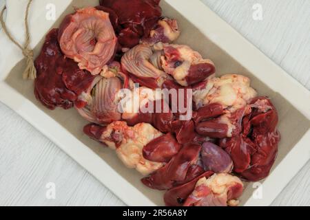 Rohe Hühnchen-Innereien auf einer Keramikplatte. Hühnermagen, -Herzen und -Lebern werden zum Kochen zubereitet. Stockfoto