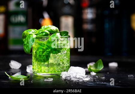 Basilikum: Alkoholisches Cocktailgetränk mit trockenem Gin, Sirup, Zitrone, Basilikum und Eis, dunkler Bartheke-Hintergrund Stockfoto