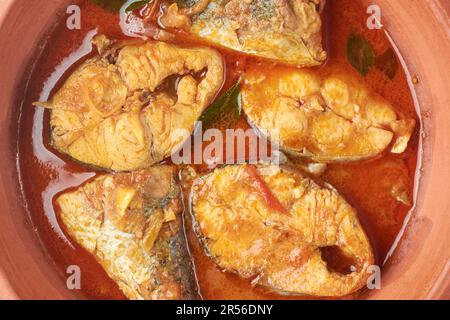 Nahaufnahme von scharfem und heißem Fischcurry in einem Tontopf oder einer Schüssel, Meeresfrüchte gekocht mit Kokosmilch, serviert asiatische Küche direkt von oben Stockfoto