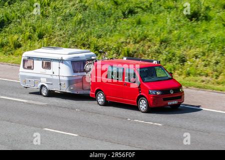 2013 Red Volkswagen Transporter T30 TDI 102 SWB LCV Window Diesel 1968 ccm Schleppen eines kleinen ERIBA-Wohnwagens auf der Autobahn M61, Großbritannien Stockfoto